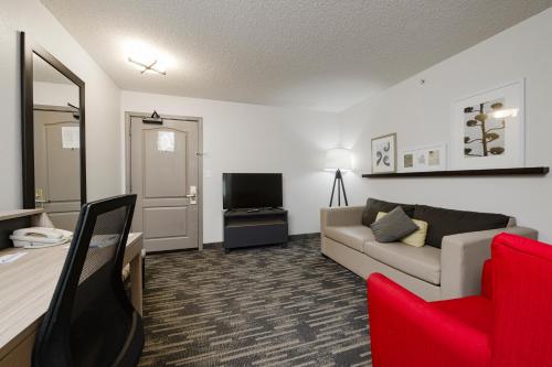 a living room with a couch and a tv at Country Inn & Suites by Radisson, Queensbury - Lake George , NY in Lake George