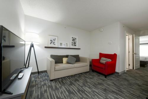 a living room with a couch and a red chair at Country Inn & Suites by Radisson, Queensbury - Lake George , NY in Lake George