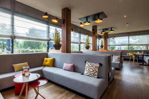 a living room with a couch and tables and windows at Holiday Inn Eindhoven Centre by IHG in Eindhoven