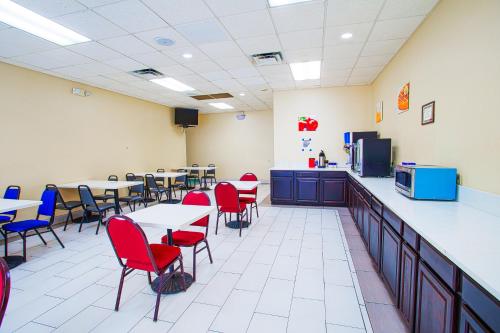 a restaurant with tables and red chairs and a counter at Americas Best Value Inn Winston-Salem in Winston-Salem