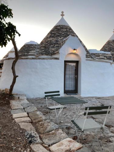une table et des chaises devant un bâtiment blanc dans l'établissement I PapaTrulli MiniResort, à Martina Franca