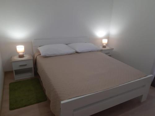 Una cama blanca con dos mesitas de noche con dos luces encima. en Sisters, en Komin