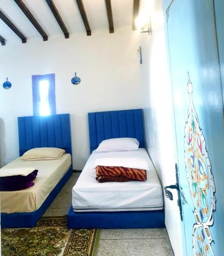 two beds in a room with blue and white walls at Casa Plasa Grande in Chefchaouene
