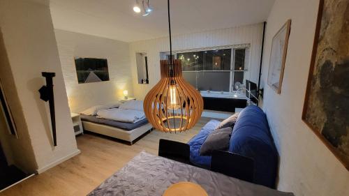 a living room with a blue couch and a chandelier at Central 1 room apartment 60m from the harbor in Sønderborg