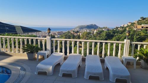 a balcony with four chairs and a swimming pool at Villa mit einzigartigem Ausblick in Alanya