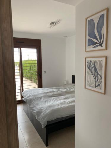 a white bedroom with a bed and a balcony at Casa Maye Terrazas de Campoamor in Orihuela