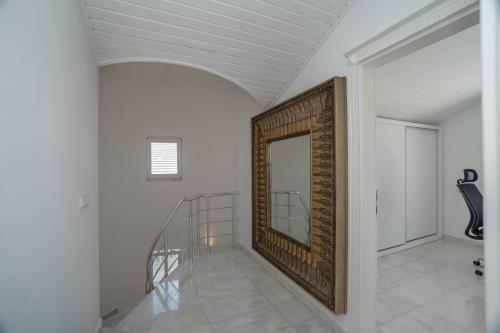 a white hallway with a staircase and a mirror at Villa mit einzigartigem Ausblick in Alanya