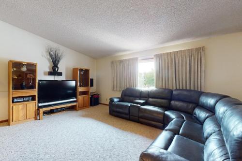 a living room with a leather couch and a flat screen tv at A Helena Haven in Helena