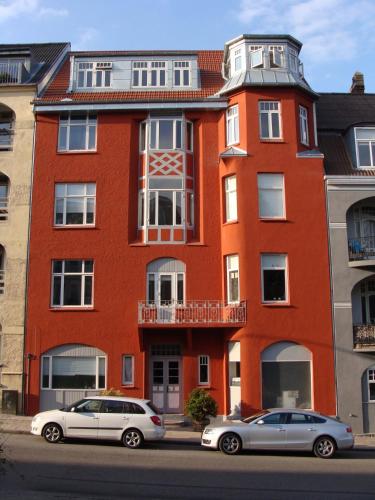 two cars parked in front of a red brick building at Central 1 room apartment 60m from the harbor in Sønderborg
