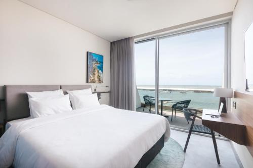 a hotel room with a bed and a desk and a window at Novotel Recife Marina in Recife