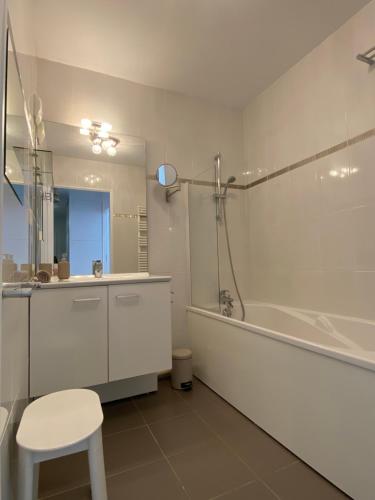 une salle de bain blanche avec une baignoire, des toilettes et un tabouret dans l'établissement Appartement Hakuna Matata 5 min Disney Parking, à Montévrain