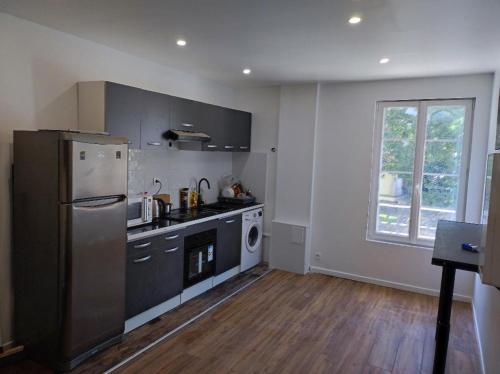 Il comprend une cuisine équipée d'un réfrigérateur en acier inoxydable et une fenêtre. dans l'établissement TRES BEL APPARTEMENT AUX PIEDS DE LA GARe, à Épinay-sur-Seine