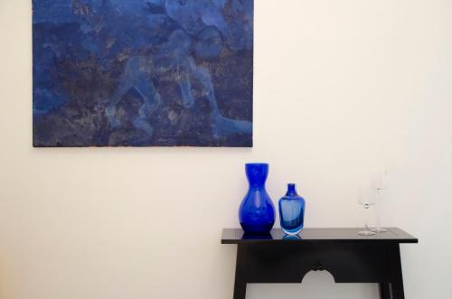 two blue vases sitting on a table next to a painting at Tancredi's Seaside Home in Granelli