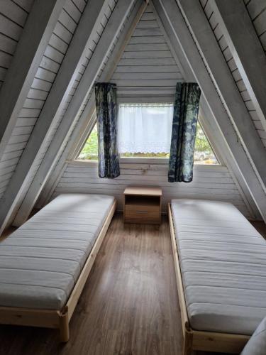 two beds in a room with a window at Cabana Ińsko-domek 20 metrów od plaży in Ińsko