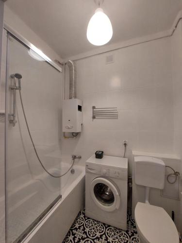 a bathroom with a toilet and a washing machine at Apartament Aleja 29 Listopada in Kraków