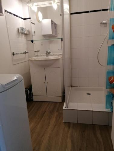 une salle de bain blanche avec un lavabo et une douche dans l'établissement Maison oleronaise, à Saint-Georges-dʼOléron