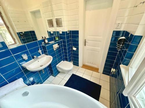 Un baño con azulejos azules, bañera y lavabo. en Apartment Siroka 14, en Praga