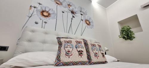 een bed met een kussen erop en bloemen aan de muur bij Lilly apartment in Catania