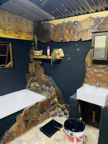 baño con 2 lavabos y pared de piedra en Cave79, en Gaborone