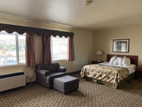 a hotel room with a bed and a chair at Travelodge by Wyndham Drumheller AB in Drumheller