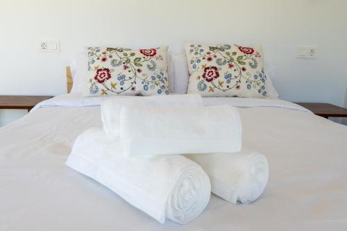 a bed with white sheets and pillows with towels at A Casa dos Caseiros ツ by Rias Baixas Rentals in Gondomar