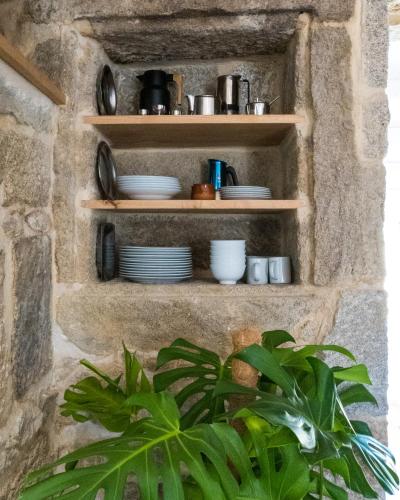 a stone wall with shelves with dishes and a plant at A Casa dos Caseiros ツ by Rias Baixas Rentals in Gondomar