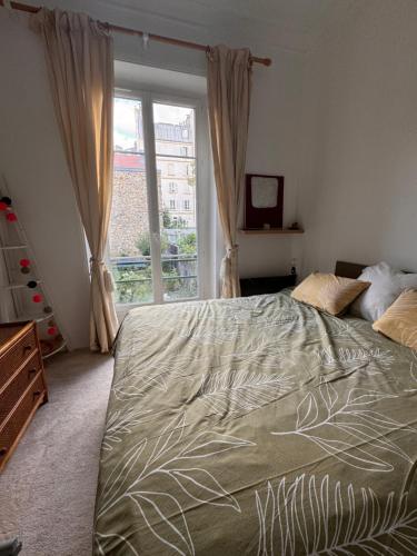 une chambre avec un grand lit et une fenêtre dans l'établissement Appartement 2 pièces charmant et paisible vue sur jardin, à Boulogne-Billancourt