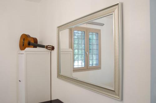 a mirror with a guitar next to a door at Tancredi's Seaside Home in Granelli