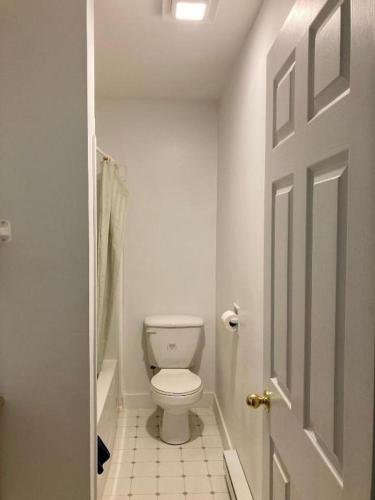 a white bathroom with a toilet and a door at Motel 99 in Grand Forks