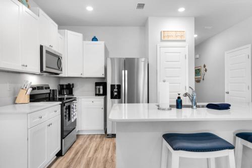 a kitchen with white cabinets and a stainless steel refrigerator at Cross Breeze-Gulf Brz-Navarre, Beaches, Boat Ramp in Gulf Breeze