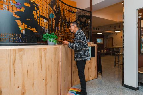 a man standing at a counter with a plant at The Haven Hostel in Thunder Bay