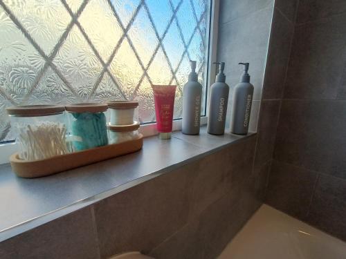 a shelf with bottles on a window in a bathroom at Alton Towers & Foxtail Barns & Oak Barns & Peak District in Wetleyrocks