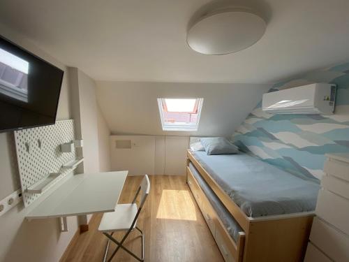 a small bedroom with a bed and a desk at Ático 22 - céntrico, aire acondicionado y parking in Vilagarcia de Arousa