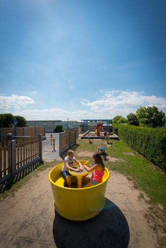 a boy and a girl riding on a ride in a yellow funnel at Park Merlo in Bredene