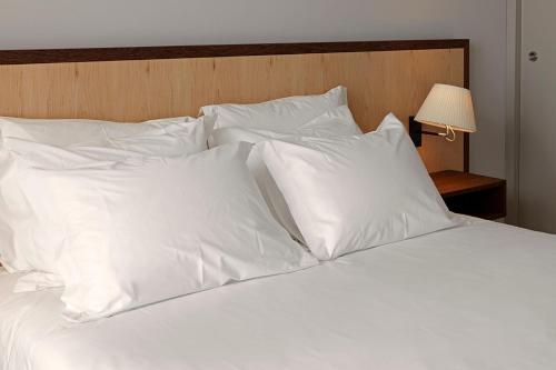 a white bed with white pillows and a lamp at Abrigo da Montanha Hotel Rural in Sabugueiro
