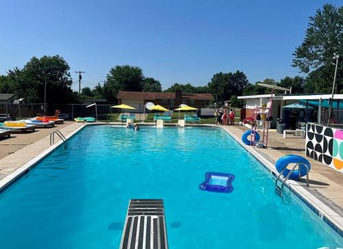 a large blue swimming pool with chairs and umbrellas at Tulsa Funk House in Tulsa