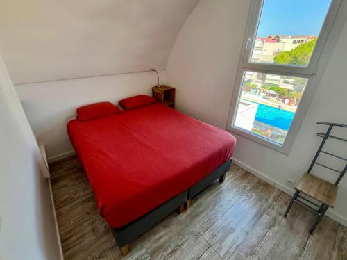 un lit rouge dans une petite pièce avec une fenêtre dans l'établissement L'appart B42, à Gruissan