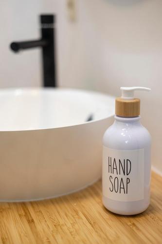 a white bottle of hand soap sitting next to a bath tub at Au petit mouton in Fernelmont