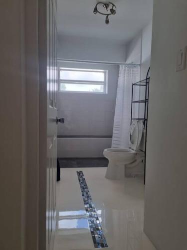 a white bathroom with a toilet and a window at Pelican key Home with the view in Simpson Bay