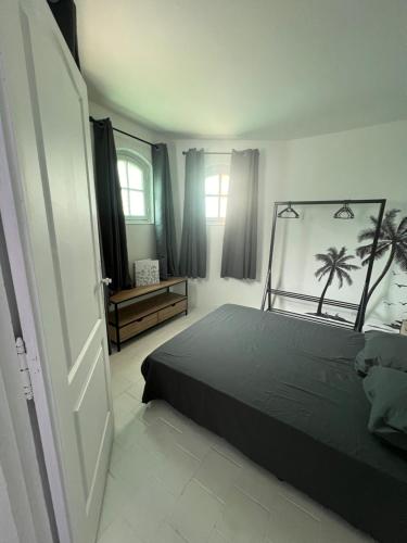 Un dormitorio con una cama negra con palmeras encima. en L'Évidence, en Saint-Raphaël