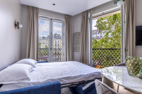 une chambre avec un lit et une grande fenêtre dans l'établissement Quartier Libre Marais, à Paris