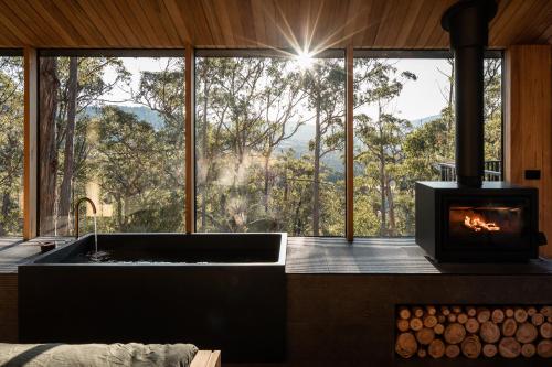 a kitchen with a tub and a fireplace in front of a window at Hunter Huon Valley Cabin Two in Glen Huon
