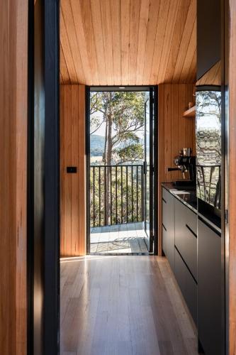a kitchen with a door leading to a balcony at Hunter Huon Valley Cabin Two in Glen Huon