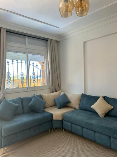 a living room with a blue couch and a window at Beachhouse Asilah in Asilah