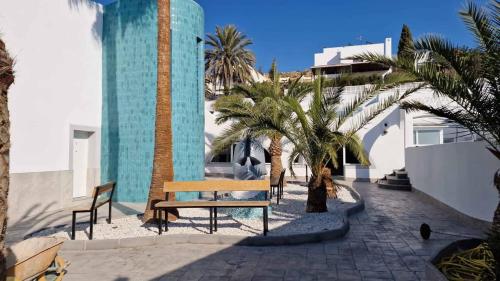 a bench and palm trees in front of a building at Gaviotas Beach Golf in Almerimar