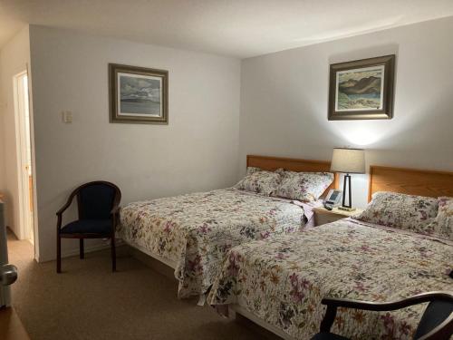 a hotel room with two beds and a chair at Motel 99 in Grand Forks