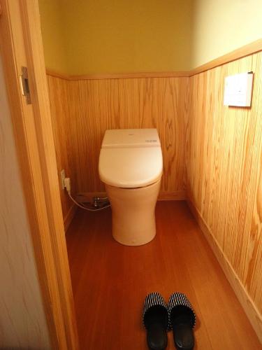 a bathroom with a toilet and two pairs of shoes at Minpaku Hiraizumi in Hiraizumi