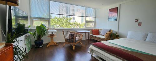 a bedroom with a bed and two chairs and windows at Mipoblues Haeundae in Busan