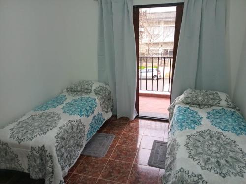 a bedroom with two beds and a door to a balcony at Amplia casa en planta alta en Av Mitre Parque Urquiza in Paraná