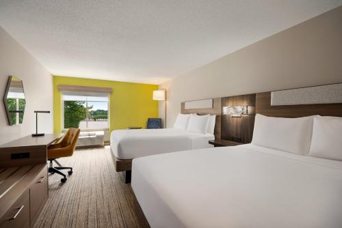 a hotel room with two beds and a desk at Holiday Inn Express Hotel & Suites Fredericksburg by IHG in Fredericksburg
